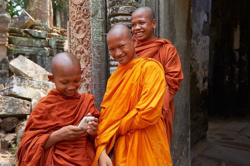 Novice monks play with their phones in the Angkor Temples